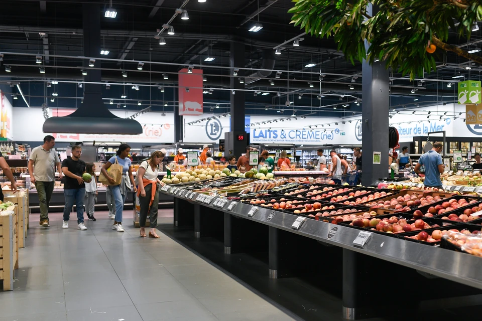 Intérieur de supermarché moderne avec clients circulant dans le rayon fruits et légumes