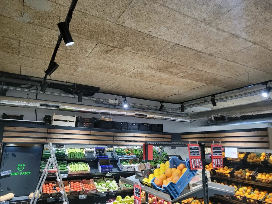 Jeune homme en pull beige et lunettes examine une vitrine r&eacute;frig&eacute;r&eacute;e de chocolaterie artisanale